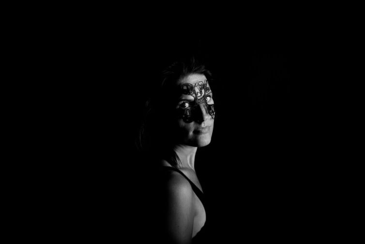 Black and white portrait of a woman with intricate face art on her forehead and eyes.