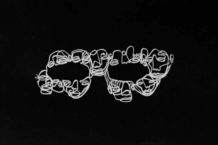 Abstract line art depicting multiple faces in a continuous design on a black background.