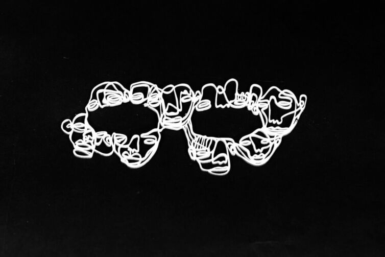 White lace eye mask made of intricate, intertwined lines on a black background.