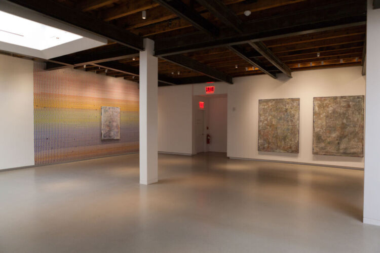 Interior view of a contemporary art gallery featuring abstract paintings on the walls.
