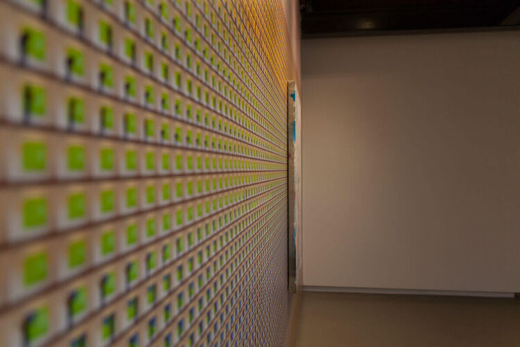 A wall covered with a pattern of green and white tiles arranged in a grid formation.