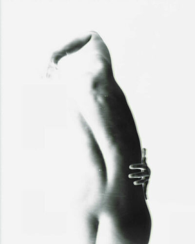 Artistic black and white photograph of a nude figure with a hand on the hip.