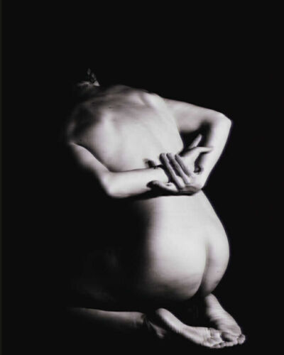 A black and white photograph of a nude figure with arms positioned behind the back.