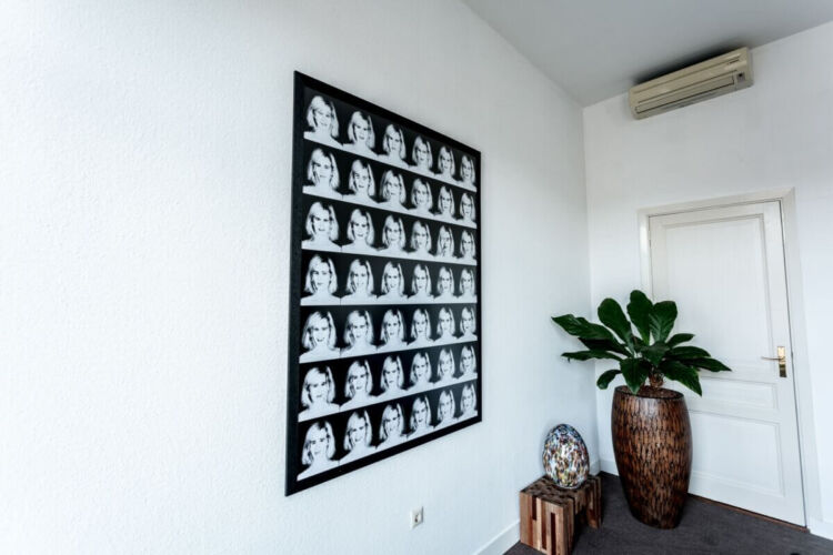 A collage of black and white portraits arranged in a grid pattern on a wall.