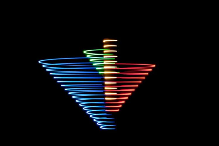 Spiral light pattern created with blue, red, green, and yellow lights against a black background.