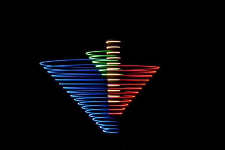 Spiral pattern created with colored lights in blue, red, green, and yellow against a black background.