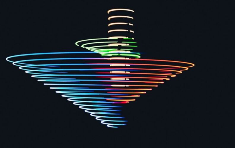 A colorful spinning top creating light trails in a dark background.