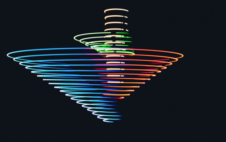A colorful spinning top creating light trails in various colors against a dark background.