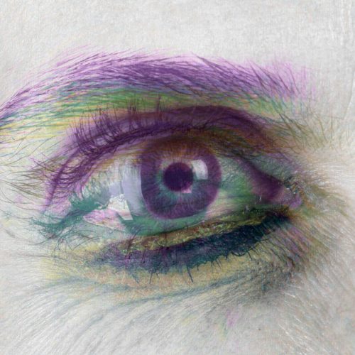Close-up view of a human eye featuring vibrant purple and green color effects.
