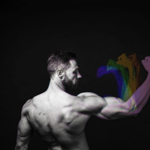 A muscular man flexing his arm, showcasing defined biceps against a dark background.